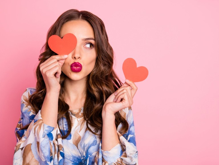 Close-up portrait of her she nice-looking attractive lovely coquettish cheerful cheery wavy-haired girl holding in hands two small little heart sending you kiss, singles concept isolated over pink pastel background